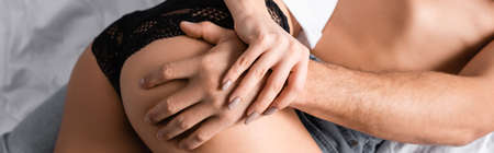 Cropped view of shirtless man touching buttocks of sensual woman, banner