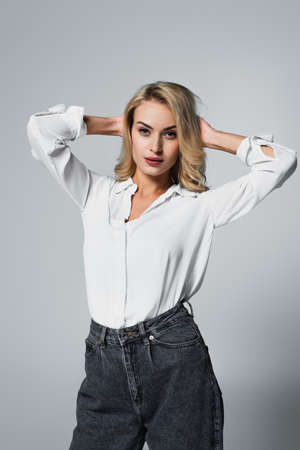 sensual woman in white shirt posing with hands behind head on grayの写真素材