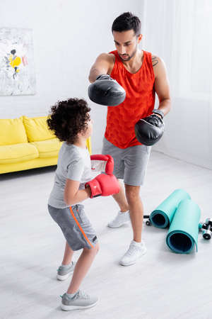 Muslim father and son boxing near sport equipment at homeの写真素材