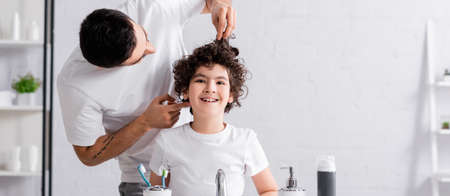 Muslim man touching hair of cheerful son in bathroom, bannerの写真素材