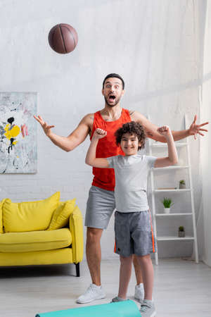 Excited arabian father and son standing near basketball at homeの写真素材