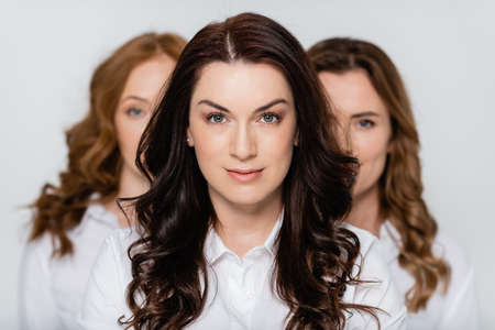 Brunette woman standing near friends isolated on grayの写真素材