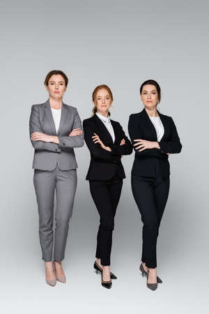 Businesswomen in formal wear posing on gray backgroundの写真素材