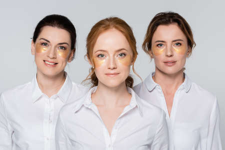 Adult women with eye patches smiling at camera isolated on gray