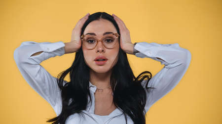 shocked businesswoman touching head isolated on yellowの写真素材