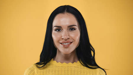portrait of joyful, brunette woman smiling at camera isolated on yellow