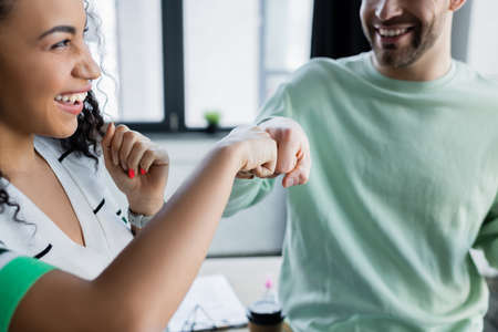 cheerful african american businesswoman doing fist bump with colleague on blurred backgroundの写真素材