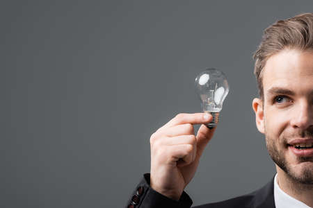 cropped view of positive businessman holding light bulb isolated on grayの写真素材