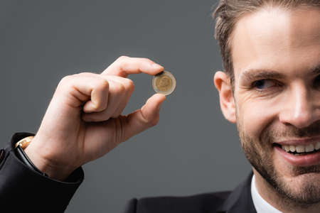 cropped view of joyful businessman showing coin isolated on grayの写真素材