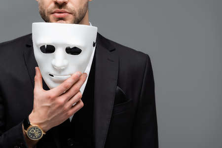 cropped view of businessman holding face mask isolated on gray