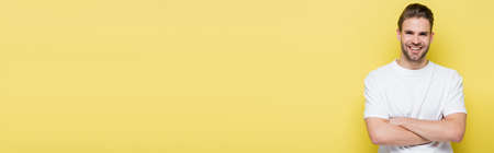 happy man with crossed arms looking at camera on yellow, bannerの写真素材