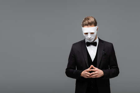 businessman in face mask standing with joined fingers isolated on grayの写真素材