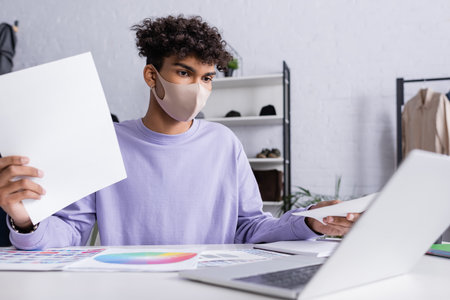 African american owner of showroom in protective mask working with papers and laptopの写真素材