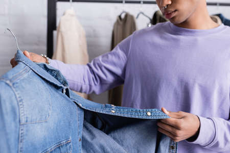 Cropped view of denim shirt in hand of african american showroom owner on blurred backgroundの写真素材