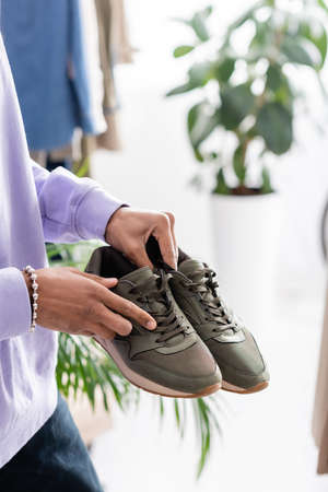 Cropped view of african american showroom proprietor holding sneakersの写真素材