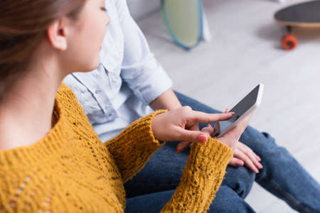 blurred teenage girl pointing with finger at digital tablet near mother