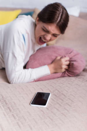 blurred teenage girl screaming near smartphone with blank screenの写真素材