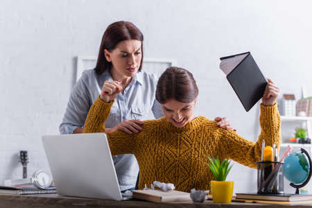 worried mother hugging upset teenage daughter with notebook near laptopの写真素材