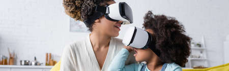 amazed african american child and smiling mother gaming in vr headsets at home, banner