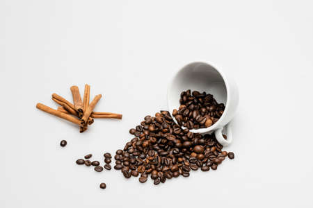 cinnamon sticks near cup with fresh coffee beans on whiteの写真素材