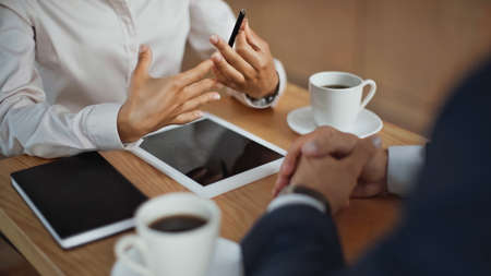 cropped view of multiethnic partners during business meeting in cafeの写真素材