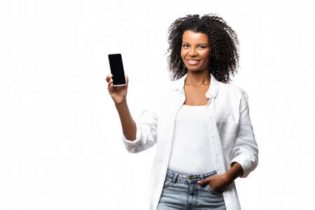 Smiling african american woman holding smartphone with blank screen isolated on white