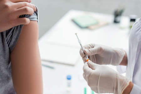 Cropped view of doctor holding syringe near arm of patient