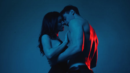 sexy couple kissing while standing on blue