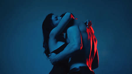 passionate woman in bra hugging sexy and shirtless man on blueの写真素材
