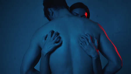 brunette woman scratching back of shirtless man on blueの写真素材