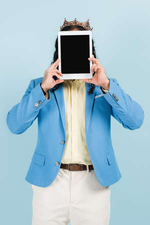 man in jacket and crown covering face while holding digital tablet with blank screen isolated on...
