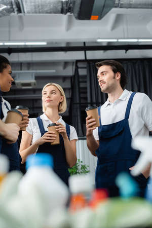 Multiethnic colleagues of cleaning service holding paper cups in office