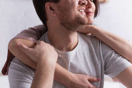 Cropped view of smiling man touching hand of wife on blurred background