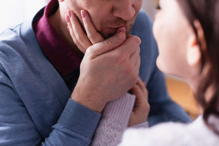 Adult man kissing hand of wife on blurred foreground