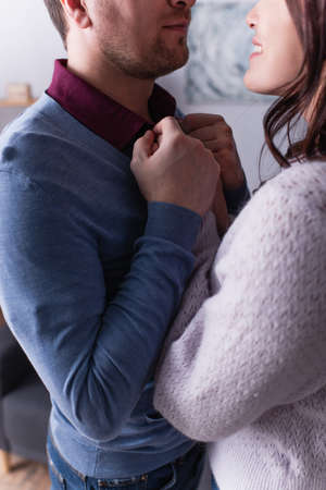 Cropped view of smiling woman holding hands of husband at home