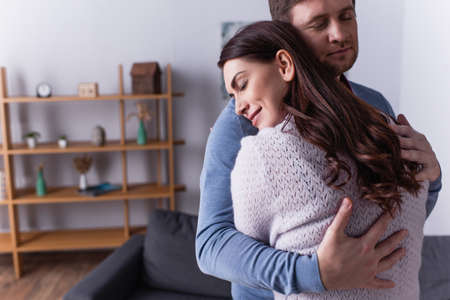 Adult couple hugging with closed eyes at home