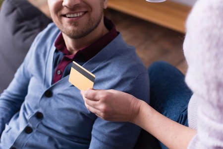 Cropped view of credit card in hand of woman near smiling husband on burred backgroundの写真素材