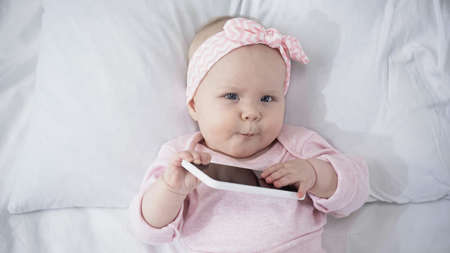 top view of infant holding smartphone with blank screenの写真素材