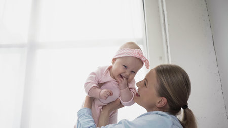 smiling woman holding in arms infant daughter in headband