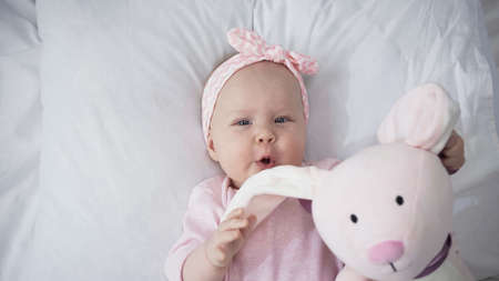top view of infant girl holding soft toy