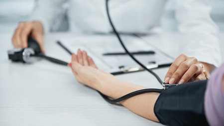 partial view of african american doctor in white coat measuring blood pressure of patientの写真素材