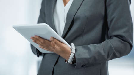 cropped view of businesswoman in gray suit using digital tablet