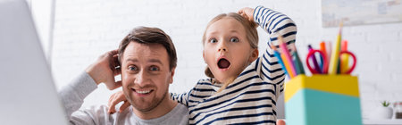 amazed father and daughter touching head while looking at camera, banner