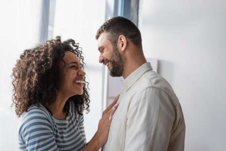 happy interracial couple smiling while hugging at home