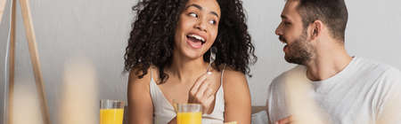 bearded man looking at african american girlfriend eating blackberry, banner