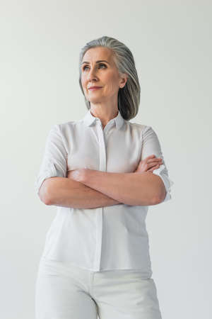 Middle aged woman looking away while standing isolated on gray
