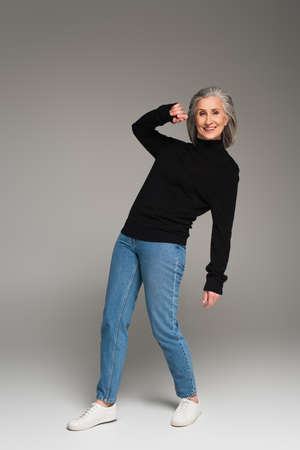 Cheerful gray haired woman posing on gray backgroundの写真素材