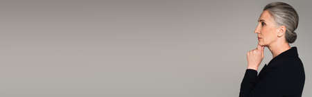 Side view of pensive businesswoman isolated on gray, banner