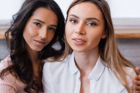 lesbian couple looking at camera in living roomの写真素材