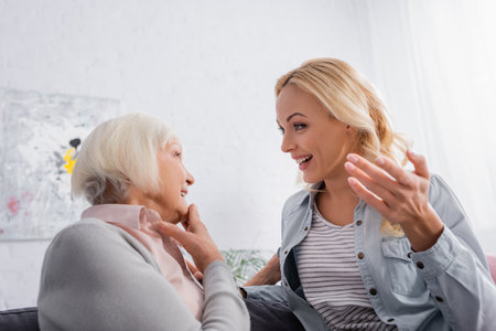 Smiling mother and daughter talking at homeの写真素材
